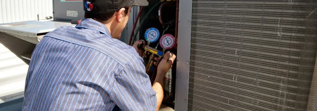 HVAC technician servicing a condenser unit in Buena Vista